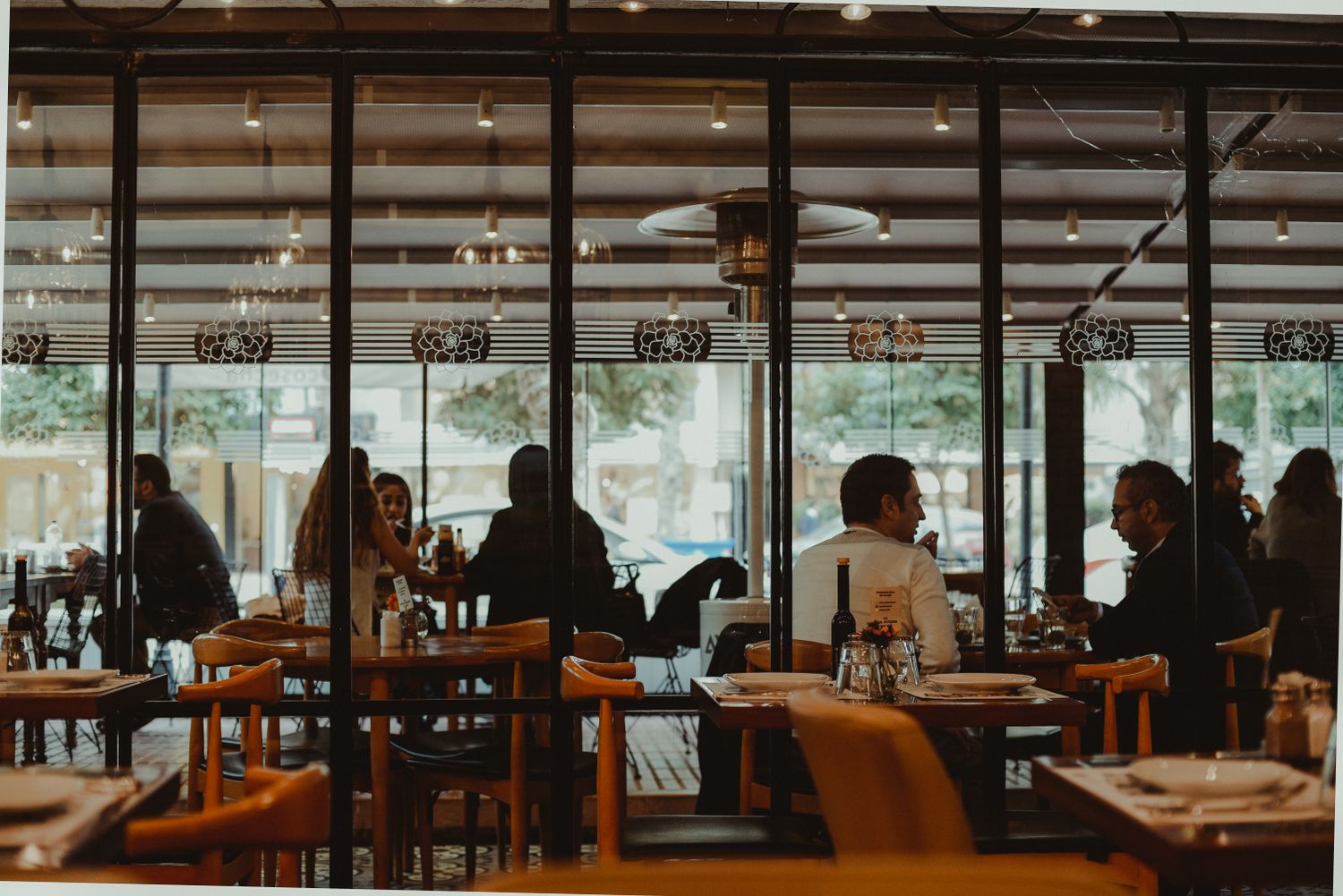 La salle du bistrot, grandes baies vitrées et tables en bois